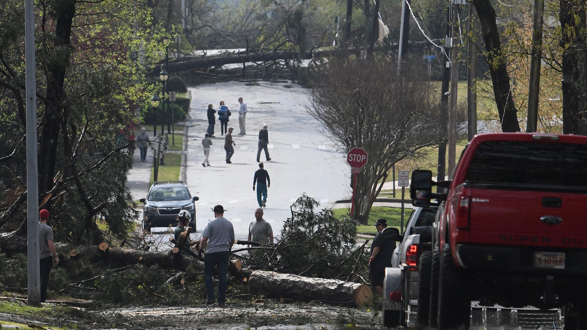Cammack Village: Menschen arbeiten daran, Bäume auf der Straße zu beseitigen, nachdem ein Tornado durch die Gegend gefegt ist.