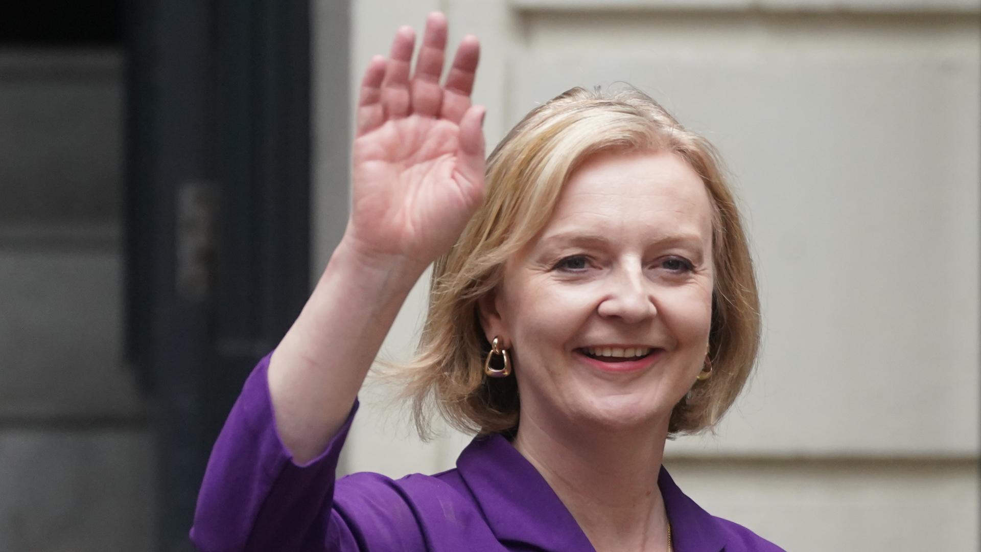 Liz Truss lacht und winkt in die Kamera. Sie hat blonde Haare. Die Haare sind halb-lang. Liz Truss lacht und winkt in die Kamera. Sie hat blonde Haare. Die Haare sind halb-lang.