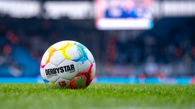 Ein Fußball mit der Aufschrift "Derby-Star" und dem Logo der Deutschen Fußball Liga liegt auf grünem Rasen.