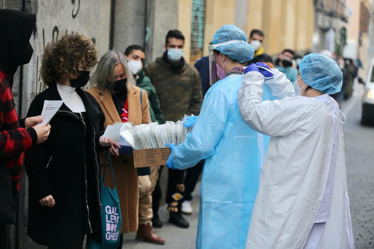 Eine Mitarbeiterin des Gesundheitswesens in Madrid hilft einer Kollegin beim Anziehen der Schutzkleidung, während sie Proben von Patienten nimmt, die vor einem öffentlichen Gesundheitszentrum auf einen Antigentest warten. Eine Mitarbeiterin des Gesundheitswesens in Madrid hilft einer Kollegin beim Anziehen der Schutzkleidung, während sie Proben von Patienten nimmt, die vor einem öffentlichen Gesundheitszentrum auf einen Antigentest warten.
