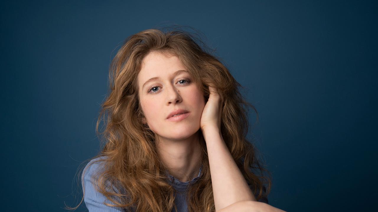 Eine junge Frau mit hellbraunen, offenen Haaren stützt ihren Kopf auf die linke Hand und blickt versonnen in die Kamera. Es ist die Jazzpianistin Clara Haberkamp. Eine junge Frau mit hellbraunen, offenen Haaren stützt ihren Kopf auf die linke Hand und blickt versonnen in die Kamera. Es ist die Jazzpianistin Clara Haberkamp.