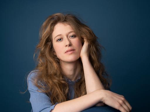 Eine junge Frau mit hellbraunen, offenen Haaren stützt ihren Kopf auf die linke Hand und blickt versonnen in die Kamera. Es ist die Jazzpianistin Clara Haberkamp.