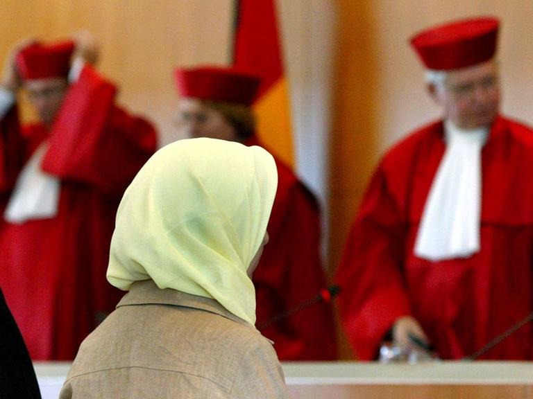 Eine Frau mit Kopftuch sitzt in einem Saal im Bundesverfassungsgericht.