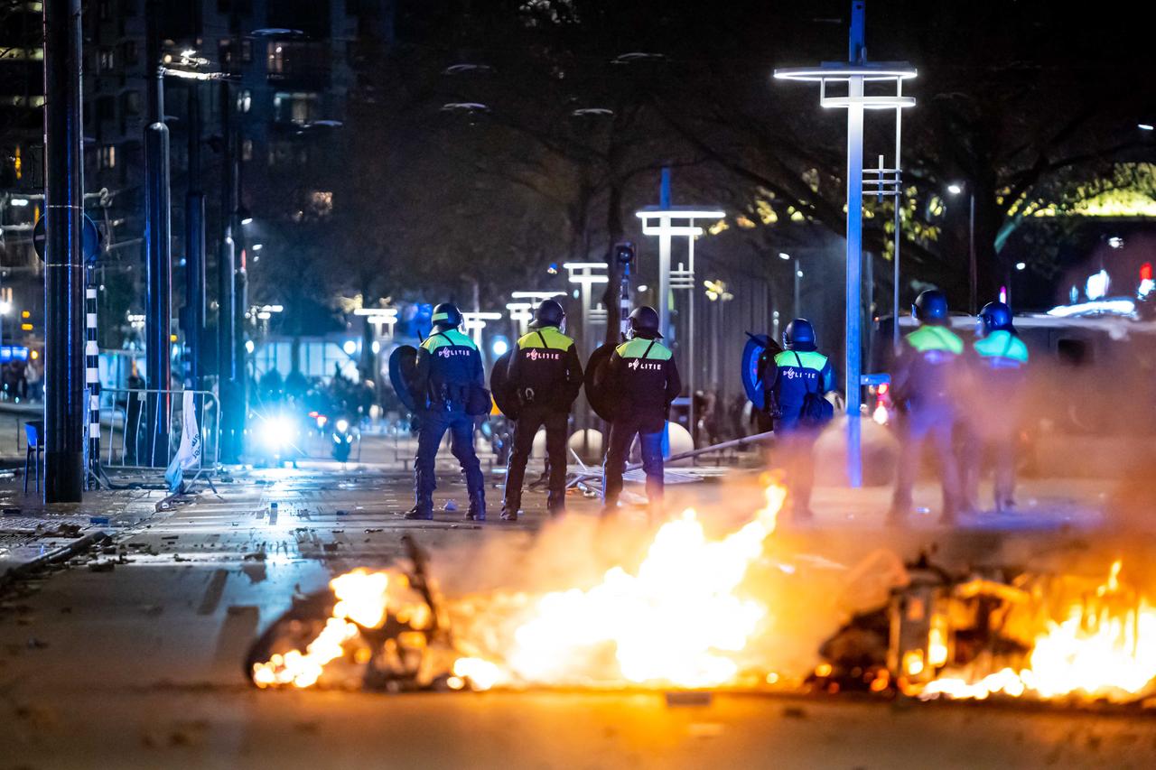 Polizisten in Rotterdam stehen während Ausschreitungen auf einer Straße vor einem Feuer. Polizisten in Rotterdam stehen während Ausschreitungen auf einer Straße vor einem Feuer.