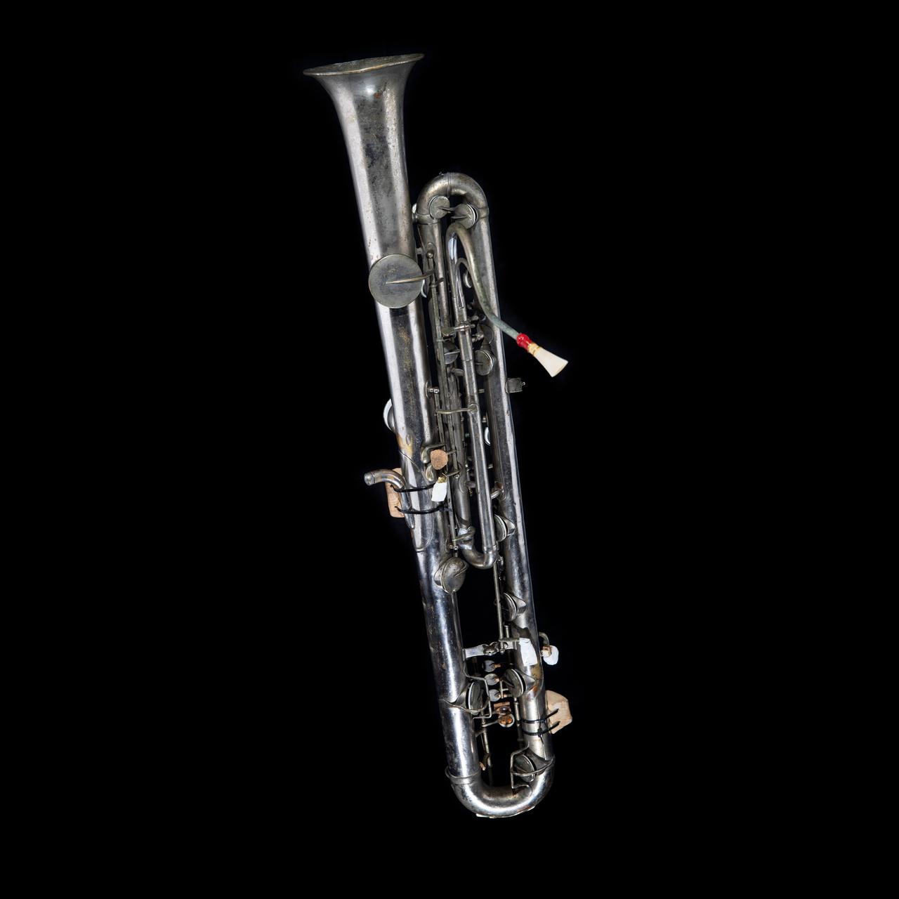 Vor schwarzem Hintergrund ist ein Blechblasinstrument zu sehen. Es ist länglich wie ein Kontrafagott, es ist aber ein Sarrusophon, das tiefste der Familie der Sarrusophone. Vor schwarzem Hintergrund ist ein Blechblasinstrument zu sehen. Es ist länglich wie ein Kontrafagott, es ist aber ein Sarrusophon, das tiefste der Familie der Sarrusophone.