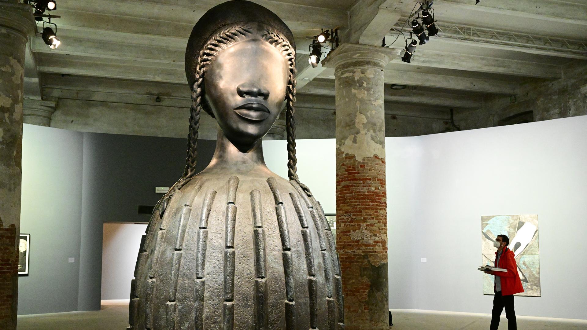 Ein Besucher sieht „Brick House“, eine Bronzeskulptur aus dem Jahr 2019 der Künstlerin Simone Leigh, während eines Pressetages auf der 59. Kunstbiennale in Venedig. Ein Besucher sieht „Brick House“, eine Bronzeskulptur aus dem Jahr 2019 der Künstlerin Simone Leigh, während eines Pressetages auf der 59. Kunstbiennale in Venedig.