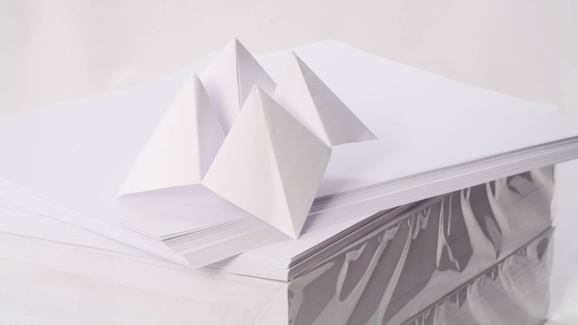 Aus Papier gebasteltes Spielzeug auf einem Stapel weißen Druckerpapieres. Aus Papier gebasteltes Spielzeug auf einem Stapel weißen Druckerpapieres.