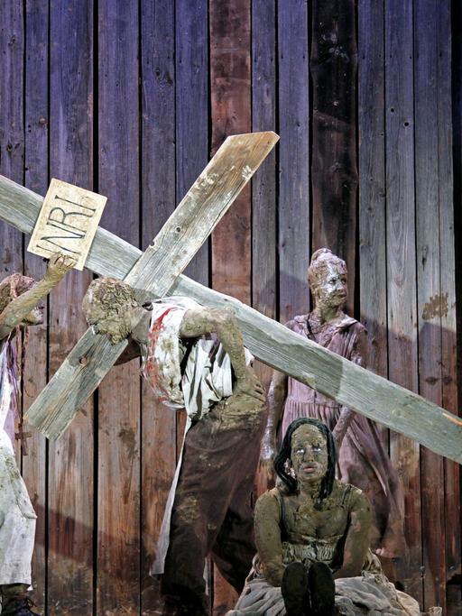 Schauspieler mit einem Kreuz auf einer Bühne.