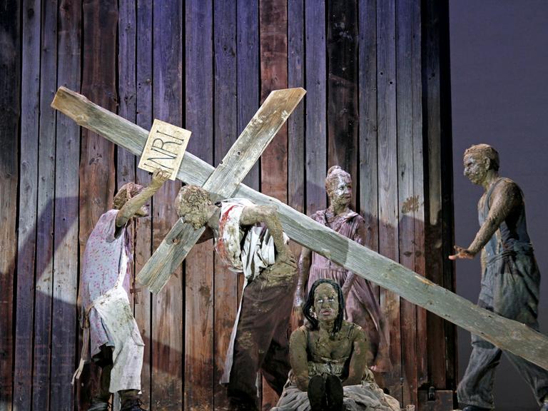 Schauspieler mit einem Kreuz auf einer Bühne.