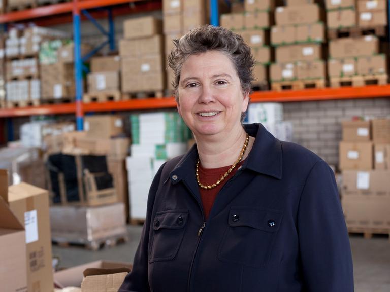 Die Sozialunternehmerin Juliane Kronen steht vor Regalen in ihrem Warenlager. 