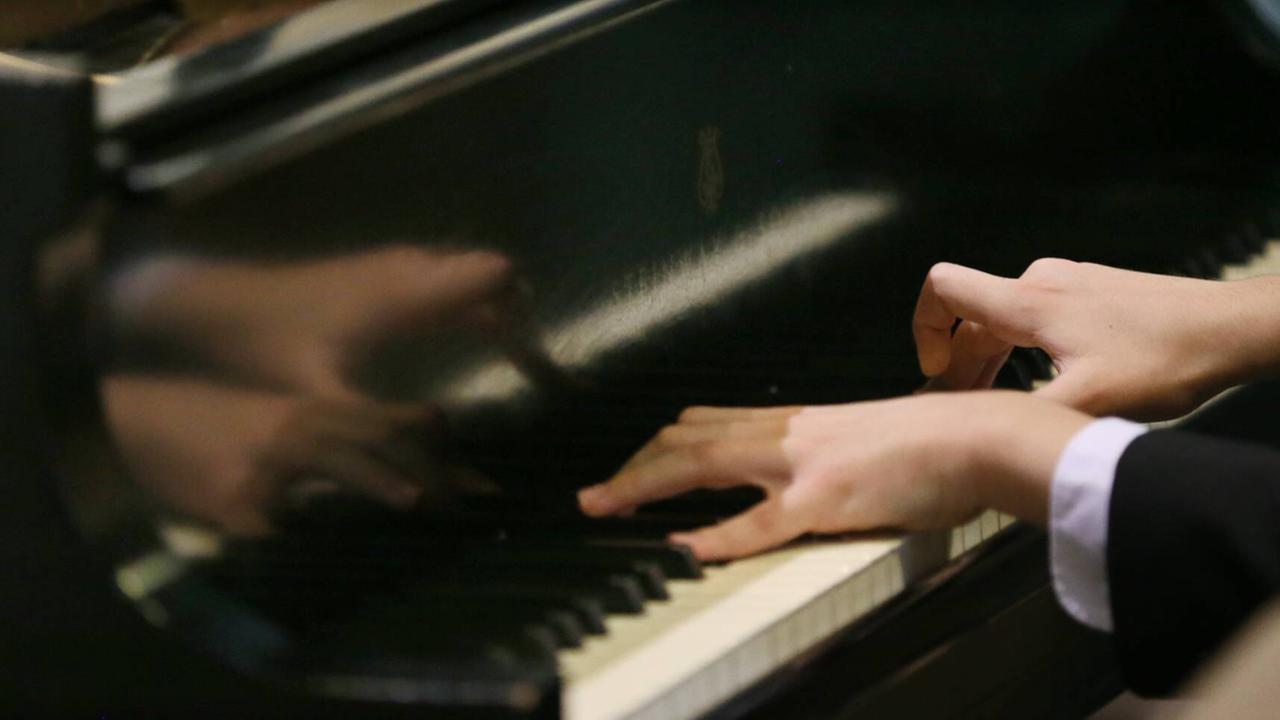 Zwei junge Hände spielen Chopin auf einerm Flügel.