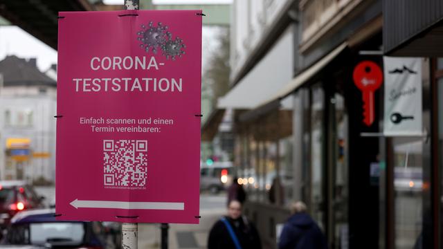 Wuppertal im Februar 2022: Fußgänger gehen an einem Schild vorbei, das auf eine Corona-Teststation hinweist. 