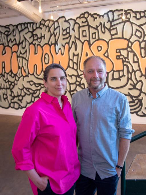 Anna Wagner und Marcus Droß, das neue Leitungsteam des Künstlerhauses Mousonturm, nach dem Pressegespräch zu ihrer neuen Aufgabe. Im Hintergrund ein Graffito mit dem Schriftzug "Hi, how are you". 
