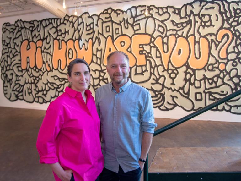 Anna Wagner und Marcus Droß, das neue Leitungsteam des Künstlerhauses Mousonturm, nach dem Pressegespräch zu ihrer neuen Aufgabe. Im Hintergrund ein Graffito mit dem Schriftzug "Hi, how are you". 