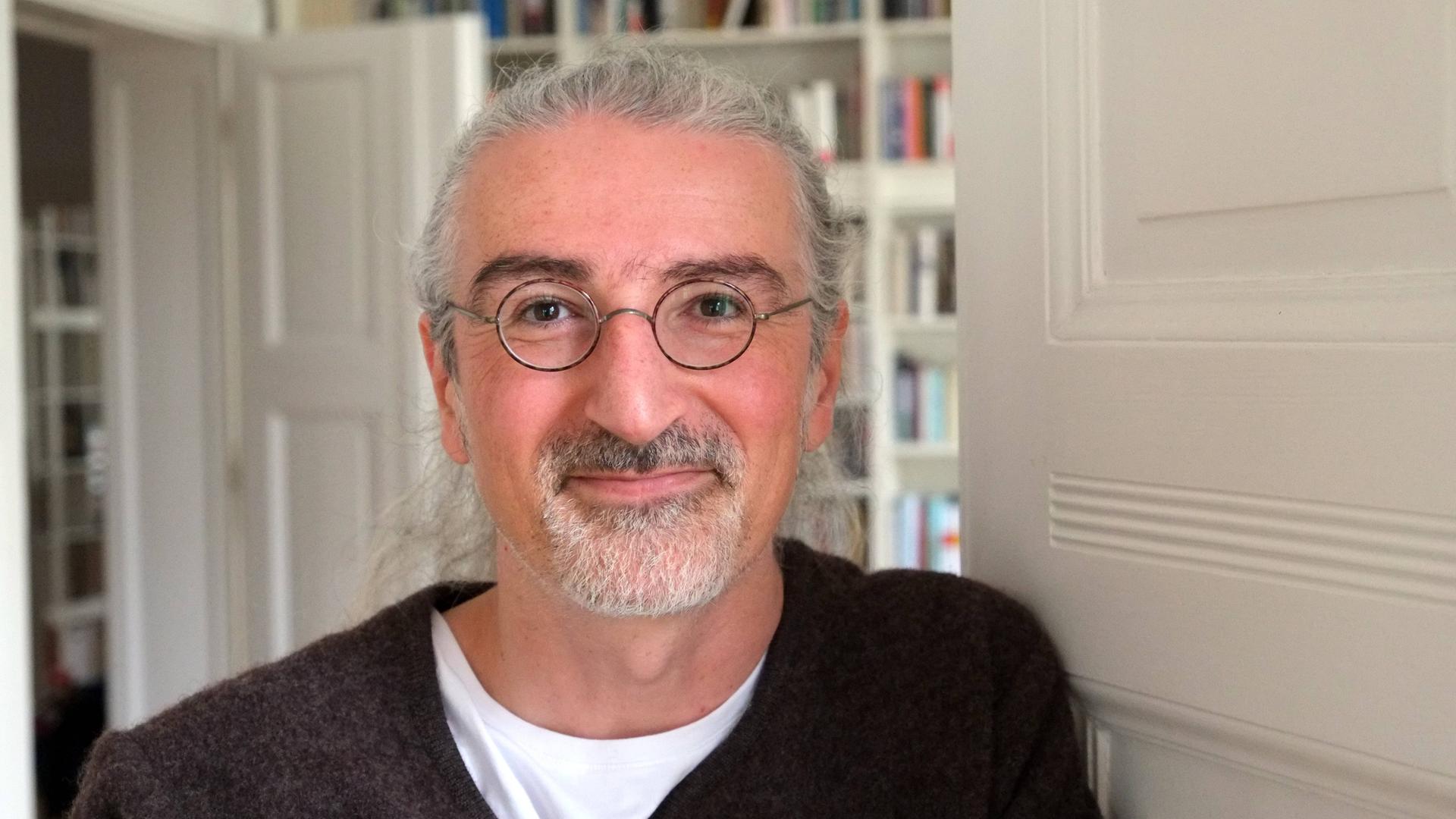 Porträtfoto des Schriftstellers Zoran Drvenkar, im Hintergrund sind weißgestrichene Türen und Bücherregale zu sehen. Porträtfoto des Schriftstellers Zoran Drvenkar, im Hintergrund sind weißgestrichene Türen und Bücherregale zu sehen.