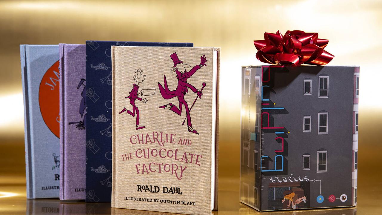Roald Dahls Kinderbuch "Charlie und die Schokoladenfabrik" ist vertikal auf einem Tisch abgestellt zu sehen.