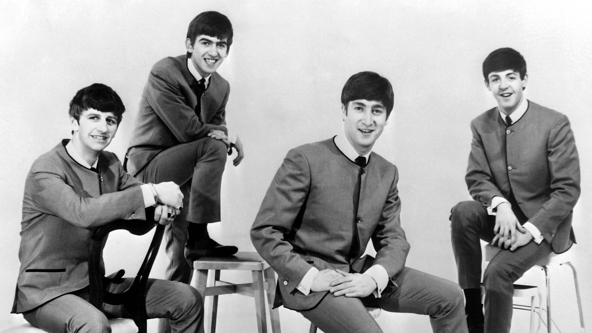 Die Beatles sitzen auf Stühlen