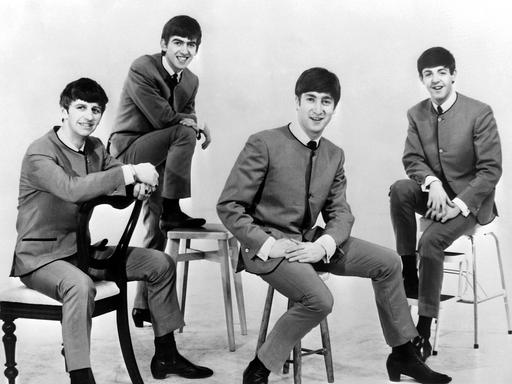 Die Beatles sitzen auf Stühlen