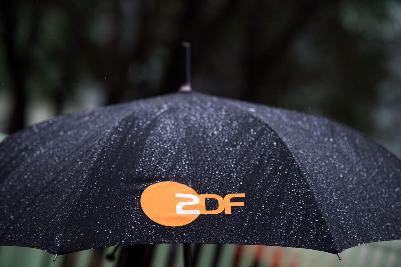 Regen fällt auf einen Regenschirm mit dem Logo des ZDF