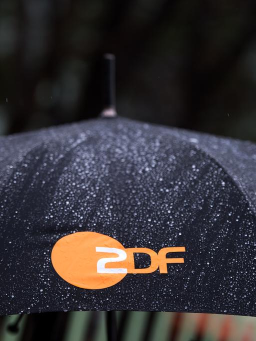 Regen fällt auf einen Regenschirm mit dem Logo des ZDF