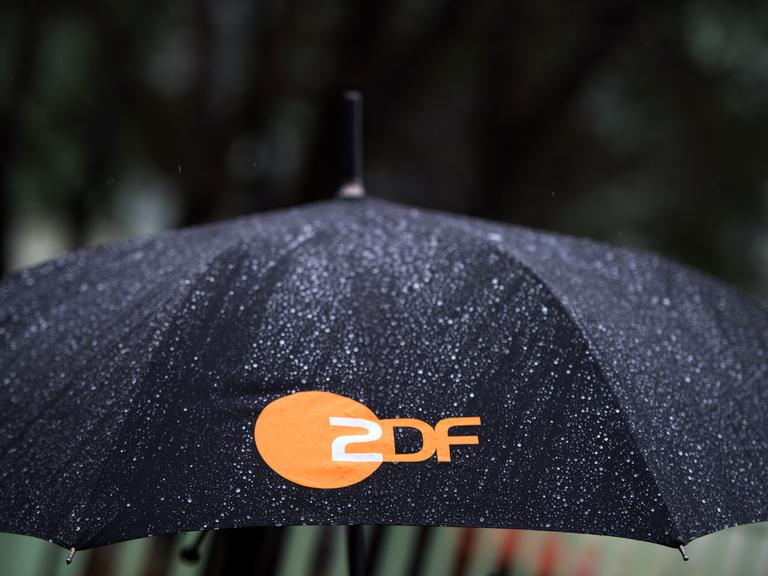 Regen fällt auf einen Regenschirm mit dem Logo des ZDF