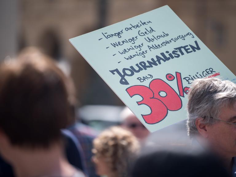Mit einem Plakat mit der Aufschrift "Journalisten bald 30% billiger" nimmt ein Journalist an einer Demonstration in der Münchener Innenstadt teil. 