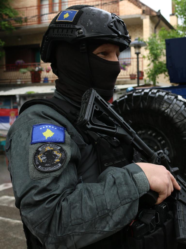 Ein kosovarischer vermummter Polizist mit Helm und Maschinenpistole. 