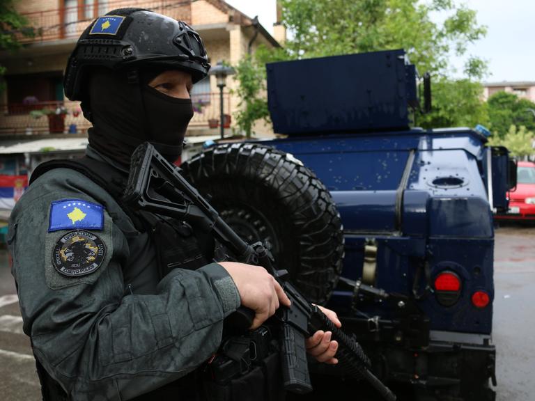 Ein kosovarischer vermummter Polizist mit Helm und Maschinenpistole. 