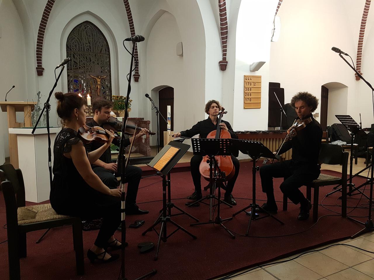 Ein Streichquartett sitzt in einer Kirche um Mikrophone und spielt. Ein Streichquartett sitzt in einer Kirche um Mikrophone und spielt.