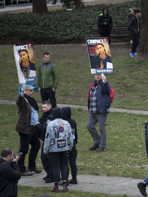 Verstreute Einzelpersonen halten am Rand einer Demonstration Bilder hoch, auf denen die Klimaaktivistin Greta Thunberg und der Schriftzug "Greta nervt" zu sehen ist.