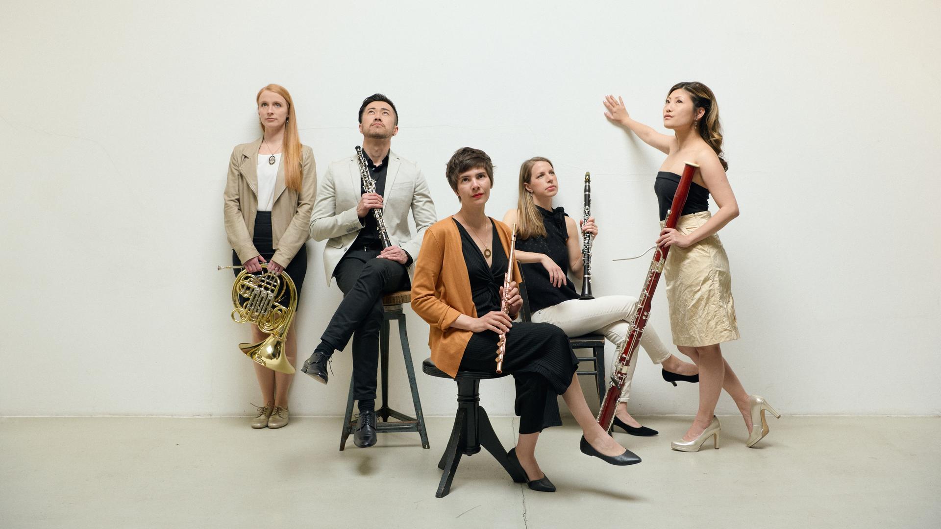 Vier Frauen und ein Mann sitzen oder stehen und alle halten ein Blasinstrument in der Hand. Vier Frauen und ein Mann sitzen oder stehen und alle halten ein Blasinstrument in der Hand.