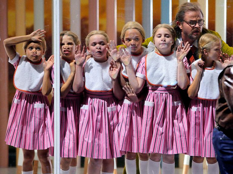 Mädchen drücken sich die Nase an einer Fensterscheibe platt, Foto aus "Rheingold" bei den Bayreuther Festspielen 2022.