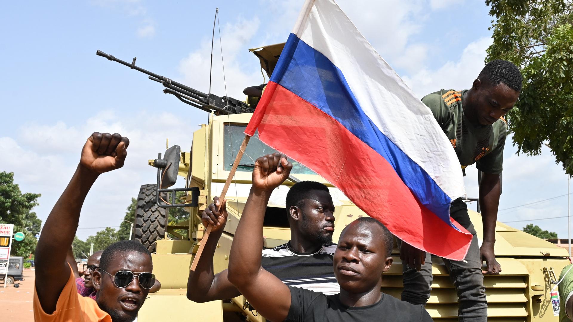 Eine Gruppe Demonstranten stehen vor einem Panzer und schwenken eine russische Flagge. Eine Gruppe Demonstranten stehen vor einem Panzer und schwenken eine russische Flagge.
