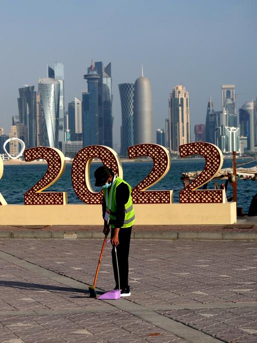 Die Hochhaus-Skyline von Doha im Hintergrund, davor eine Werbung für die Fußballweltmeisterschaft und ein einsamer Straßenfeger. 