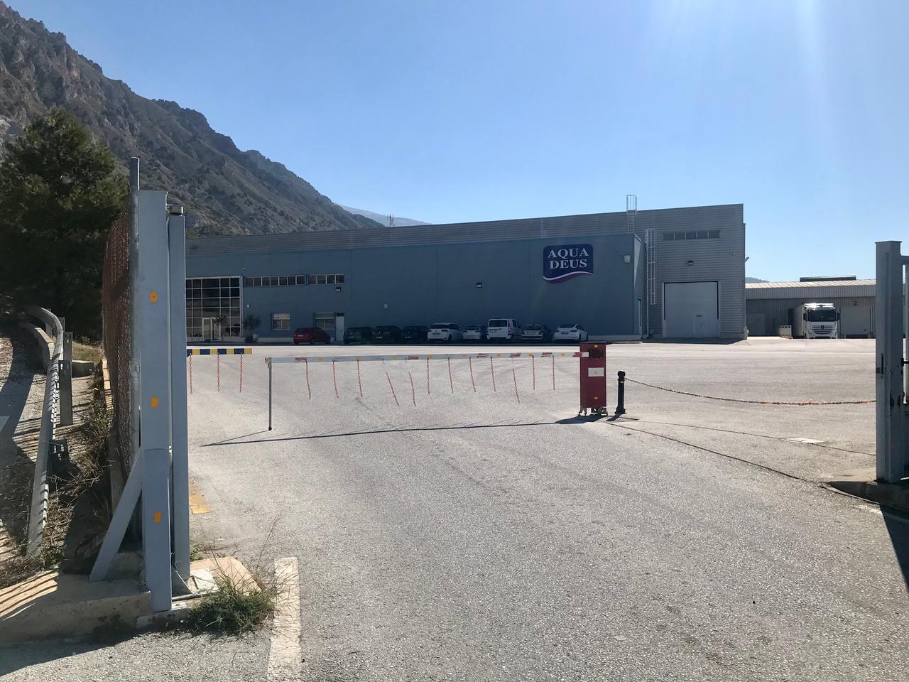 Ein flacher Beton-Gebäudekomplex steht auf einem riesigen Parkplatz mit nur wenigen Autos. Ein flacher Beton-Gebäudekomplex steht auf einem riesigen Parkplatz mit nur wenigen Autos.