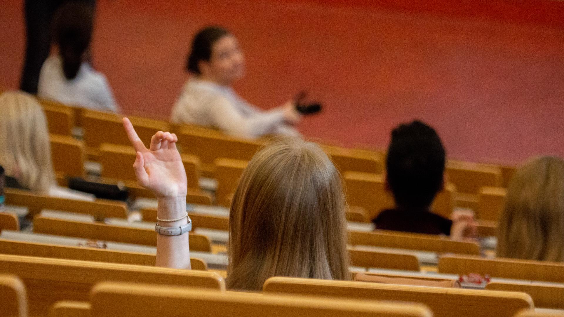 Eine junge Frau hört in einem Auditorium einer Vorlesung zu.