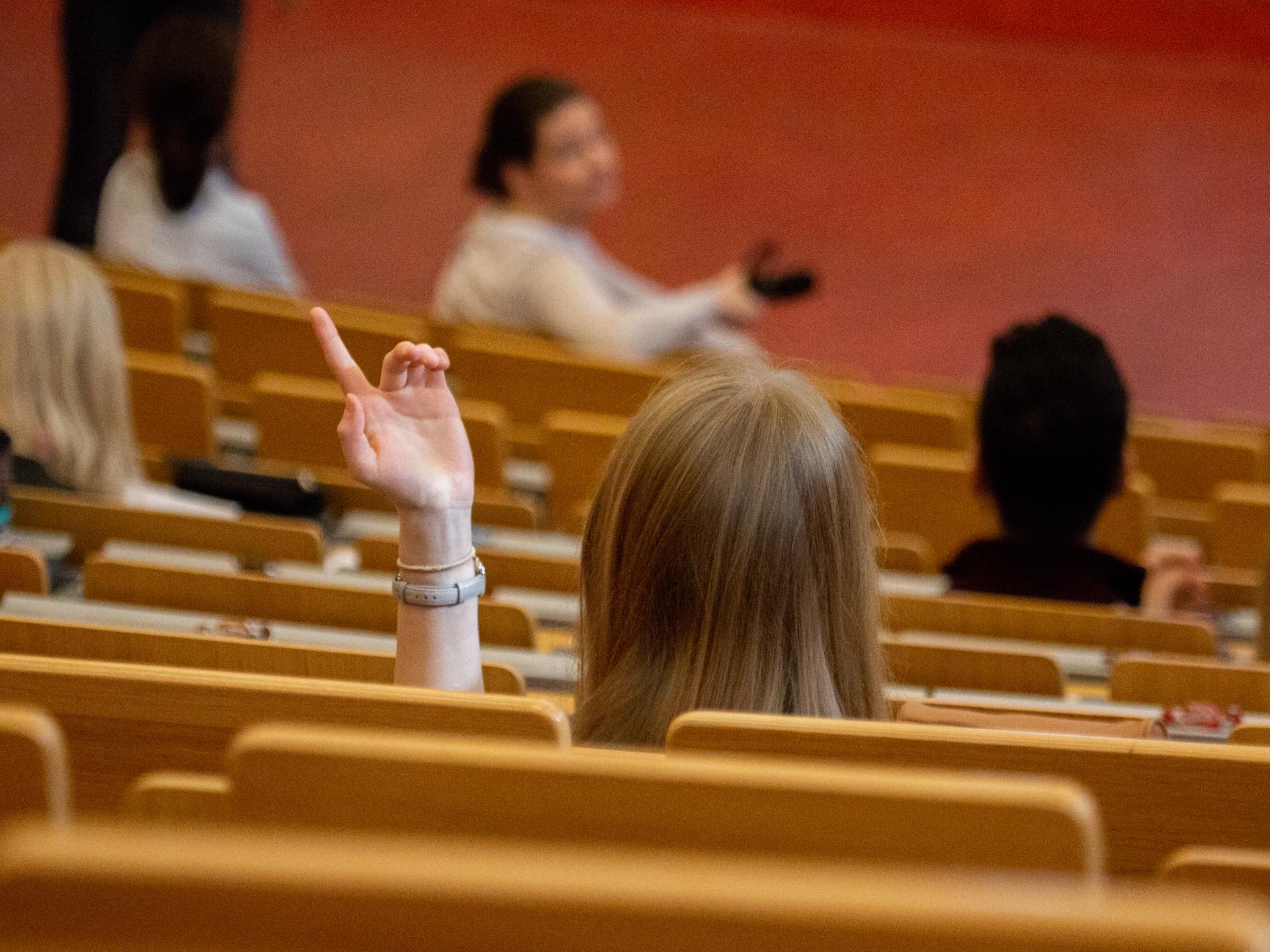 Eine junge Frau hört in einem Auditorium einer Vorlesung zu.