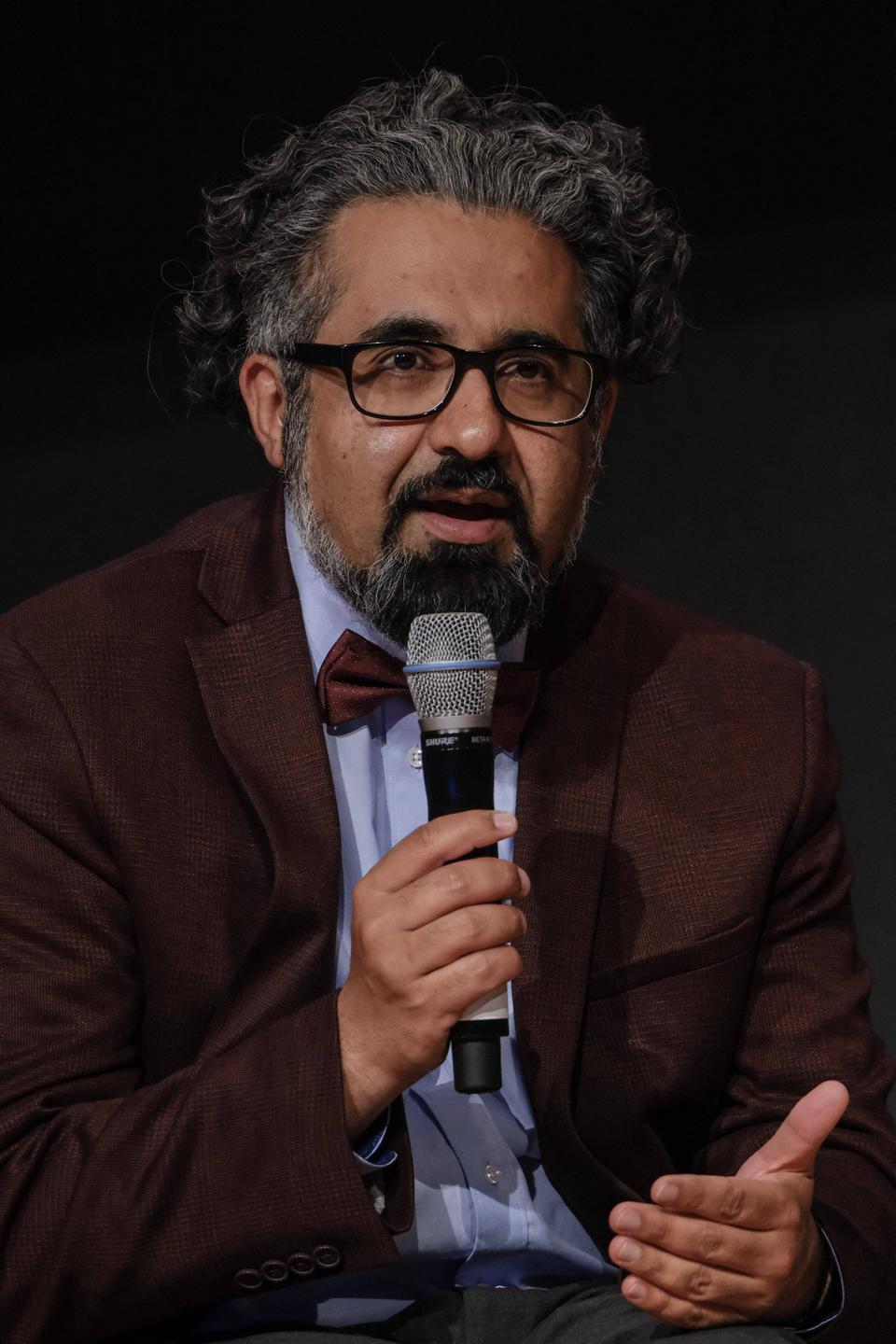 Der Islamwissenschaftler Ahmad Milad Karimi trägt ein rotbraunes Sakko und eine gleichfarbige Fliege und spricht in ein Mikrofon, das er in der rechten Hand hält. Der Islamwissenschaftler Ahmad Milad Karimi trägt ein rotbraunes Sakko und eine gleichfarbige Fliege und spricht in ein Mikrofon, das er in der rechten Hand hält.