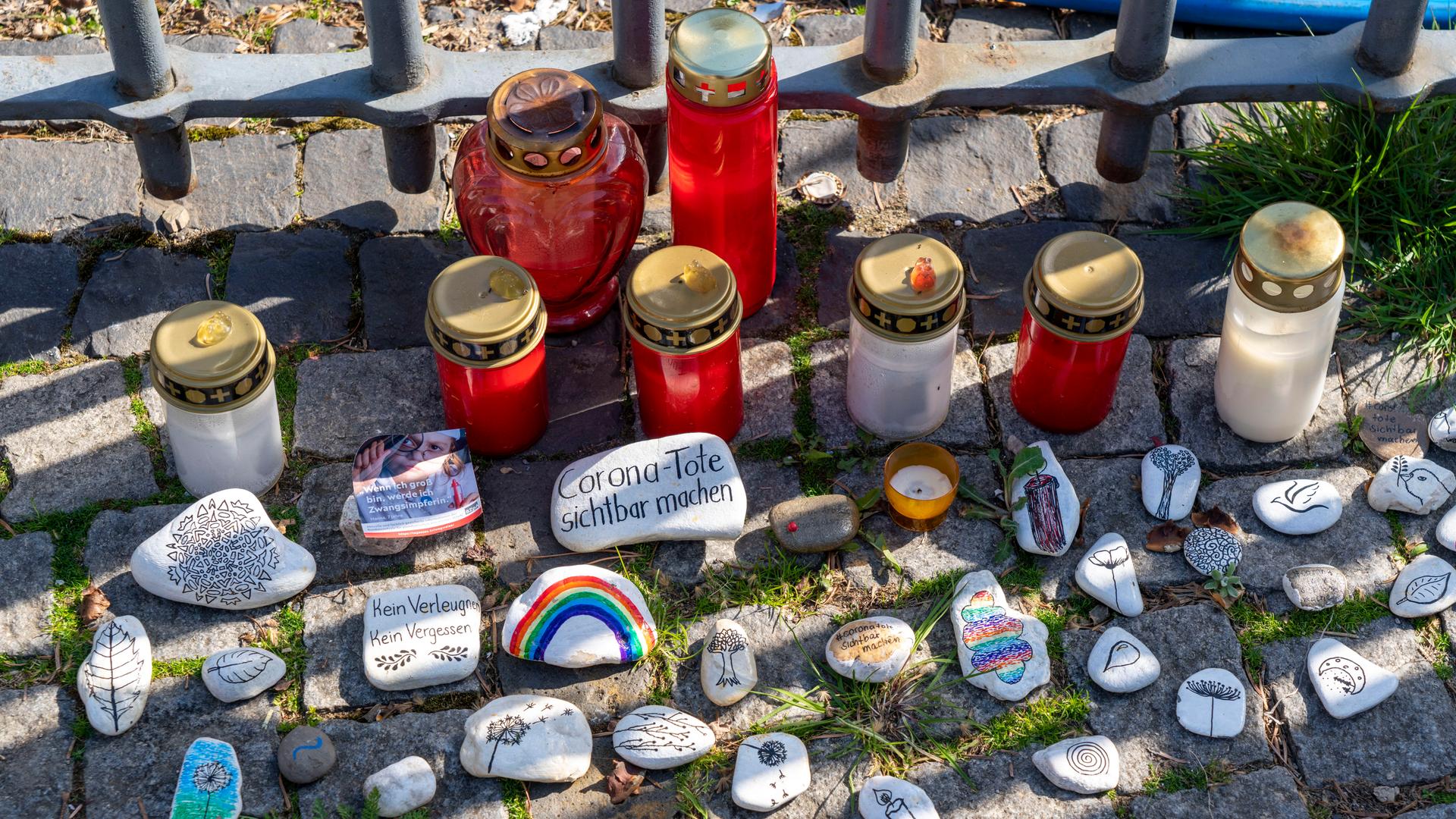 Kerzen und Steine mit Aufschrift zur Erinnerung an die Toten der Corona-Pandemie Kerzen und Steine mit Aufschrift zur Erinnerung an die Toten der Corona-Pandemie