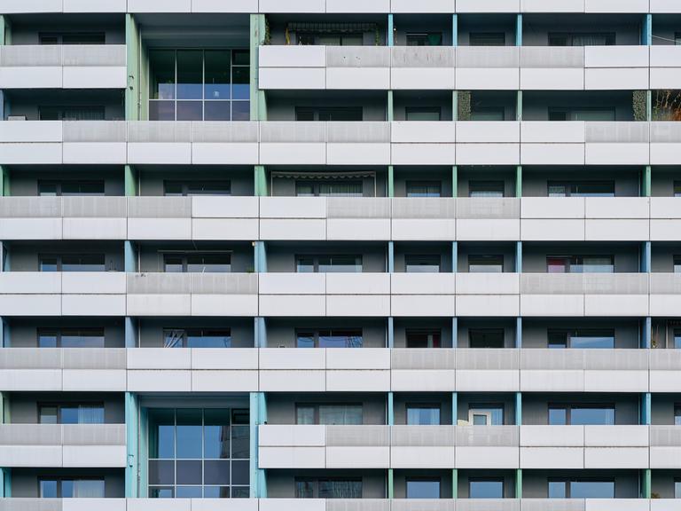 Symetrische Frontalansicht der Fassade eines sanierten DDR-Plattenbaus. 