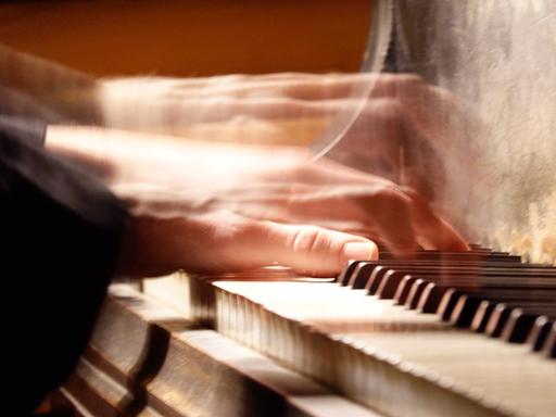 Verwischt zu sehende Hände spielen auf einer Klaviertastatur