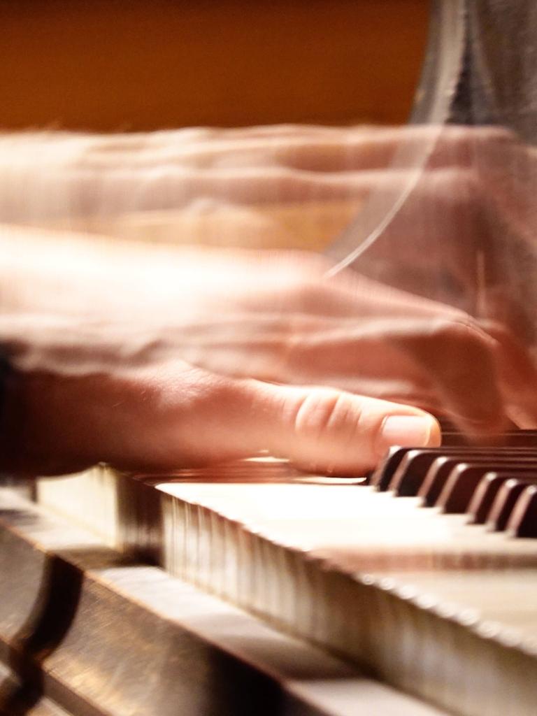 Verwischt zu sehende Hände spielen auf einer Klaviertastatur