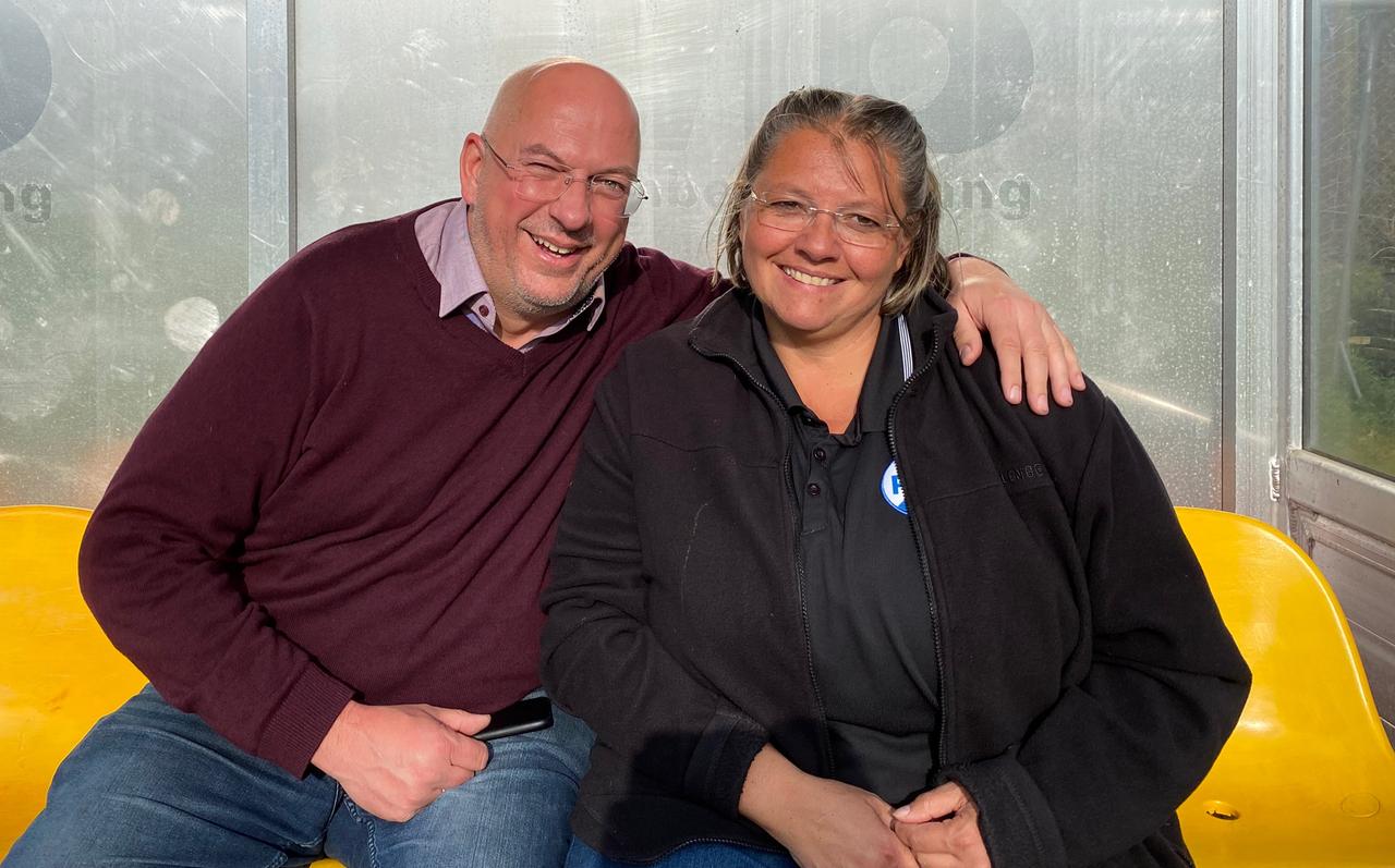 Ein Mann und ein Frau sitzen, Arm in Arm, am Rand eines Fußballplatzes: Andi und Aline Bergemann