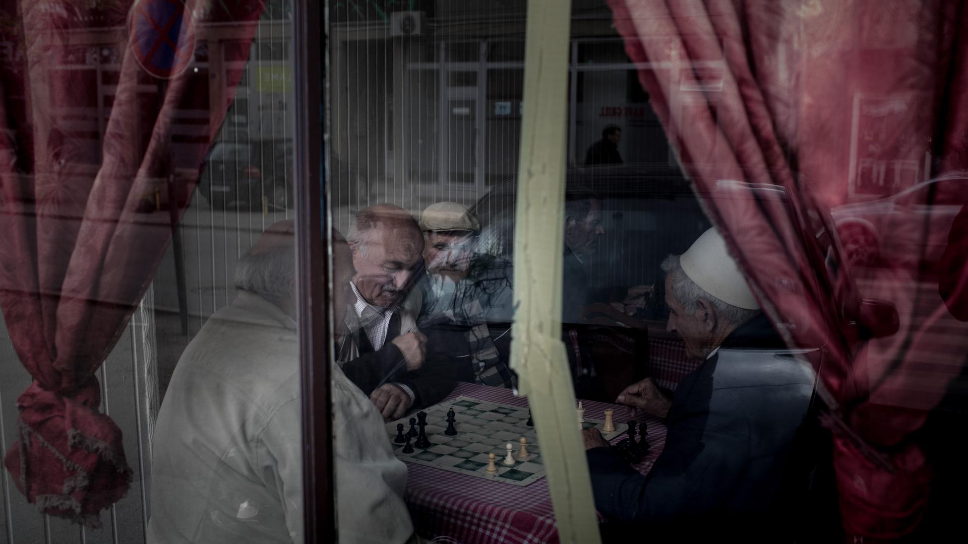 Blick durch die Scheibe eines Cafés, in dem Männer für ein Schachspiel beieinander sitzen. Blick durch die Scheibe eines Cafés, in dem Männer für ein Schachspiel beieinander sitzen.