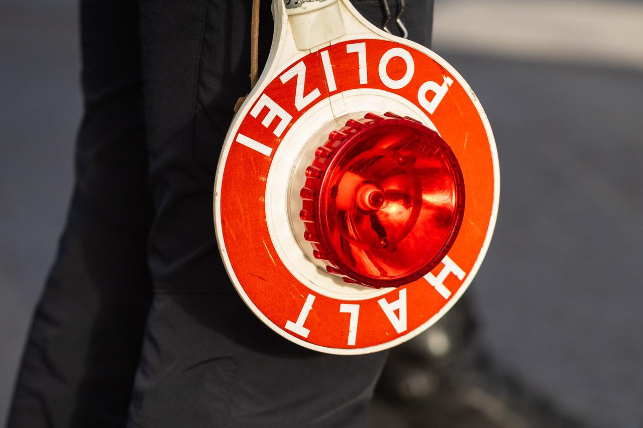 Ein Polizist hät eine Polizeikelle mit der Aufschrift "Halt, Polizei".