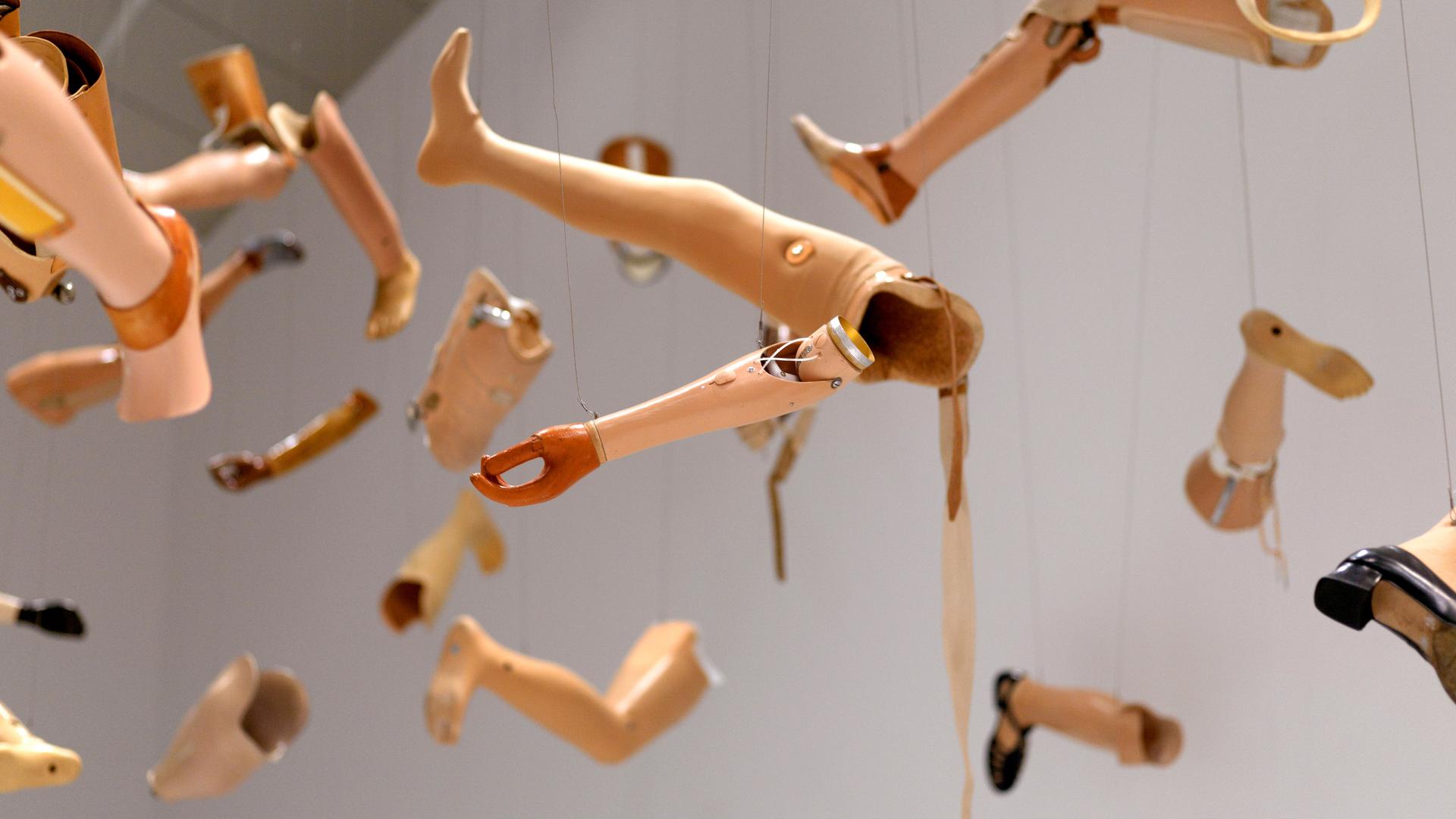 In dem Kunstwerk "On Silence" von Kader Attia hängen Prothesen von Armen und Beinen an hauchdünnen Fäden von der Decke. In dem Kunstwerk "On Silence" von Kader Attia hängen Prothesen von Armen und Beinen an hauchdünnen Fäden von der Decke.
