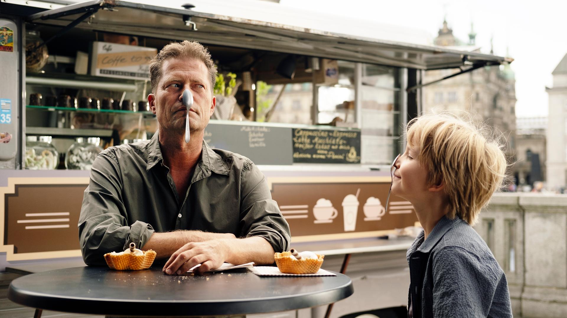 Filmszene aus dem Film "Lieber Kurt." Der Regisseur und Darsteller Til Schweiger sitzt mit einem Löffel im Gesicht an einem Tisch zusammen mit einem kleinen Jungen, der ebenfalls einen Löffel auf der Nase hat. Filmszene aus dem Film "Lieber Kurt." Der Regisseur und Darsteller Til Schweiger sitzt mit einem Löffel im Gesicht an einem Tisch zusammen mit einem kleinen Jungen, der ebenfalls einen Löffel auf der Nase hat.