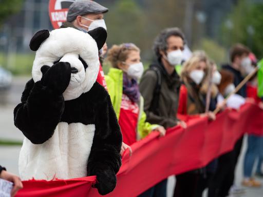 Ein als Panda verkleideter Umweltaktivist steht bei einer Demonstration für mehr Klimaschutz vor dem Bundeskanzleramt in einer Menschenkette.