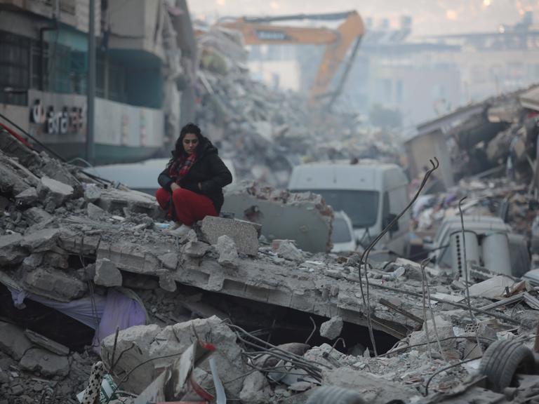 Eine Frau sitzt auf den Trümmern eines vollkommen zerstörten Hauses in der türkischen Stadt Iskenderun. 