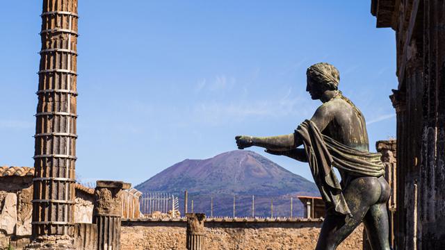 Statue des Apollo in der antiken Stadt Pompeji, Kampanien, im Hintergrund der Vulkan Vesuv